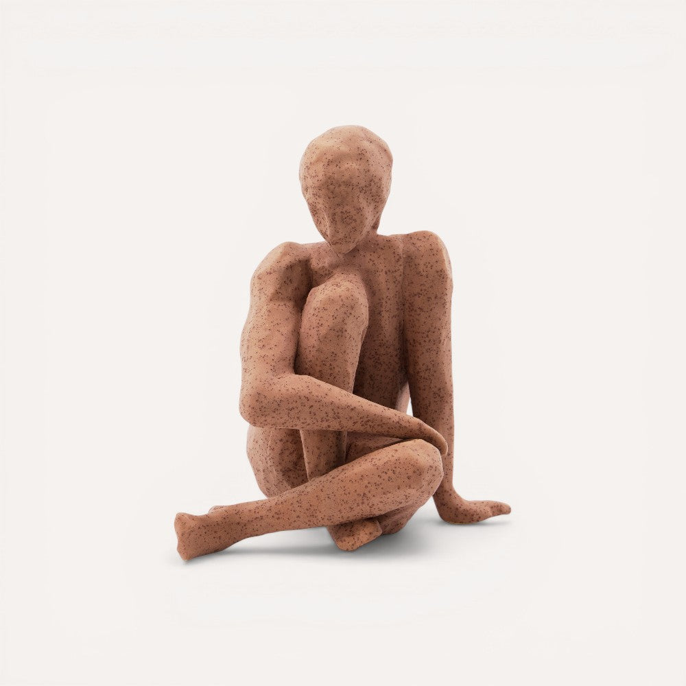 Brown abstract sculpture of a seated figure.