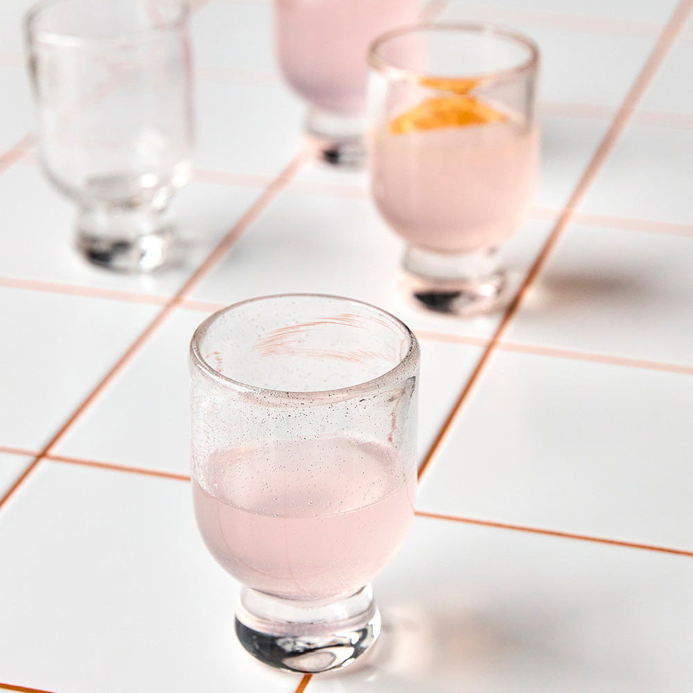 Clear glass with pink liquid on a tiled surface