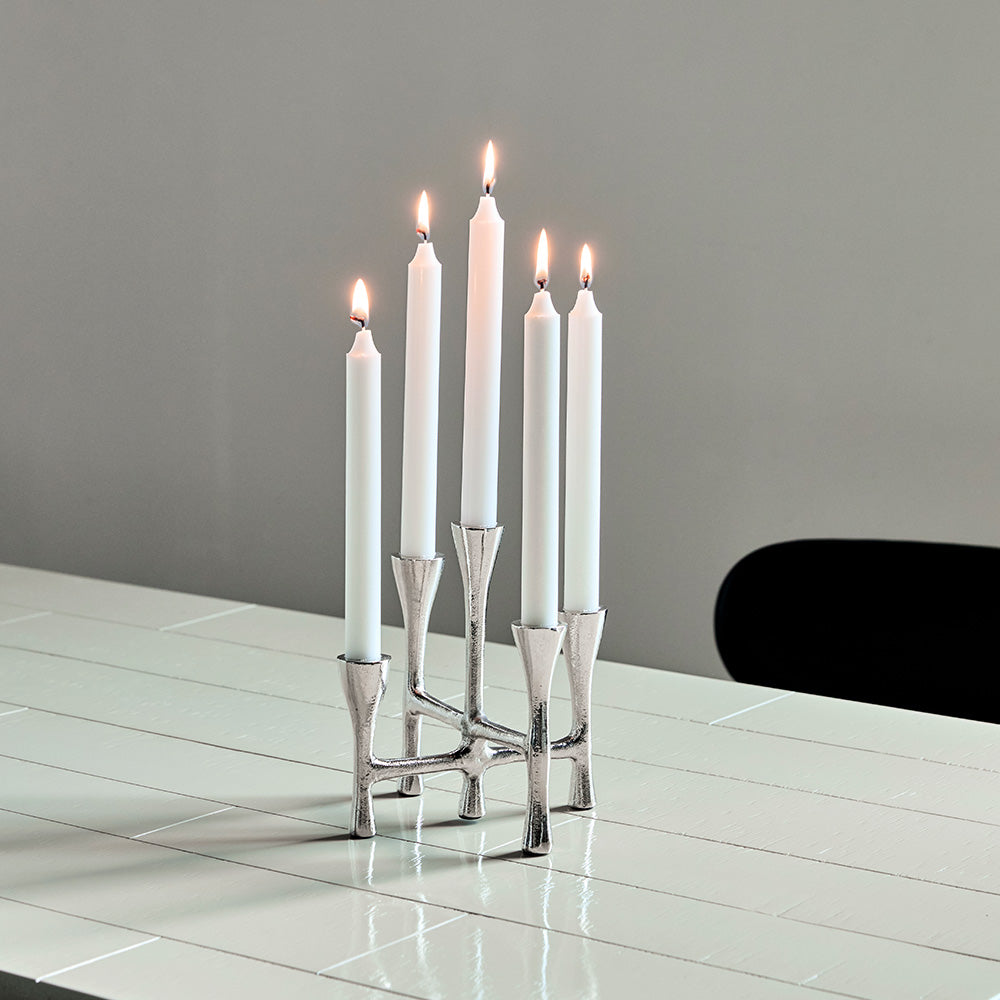 Silver candle holder with six white candles on a reflective surface.