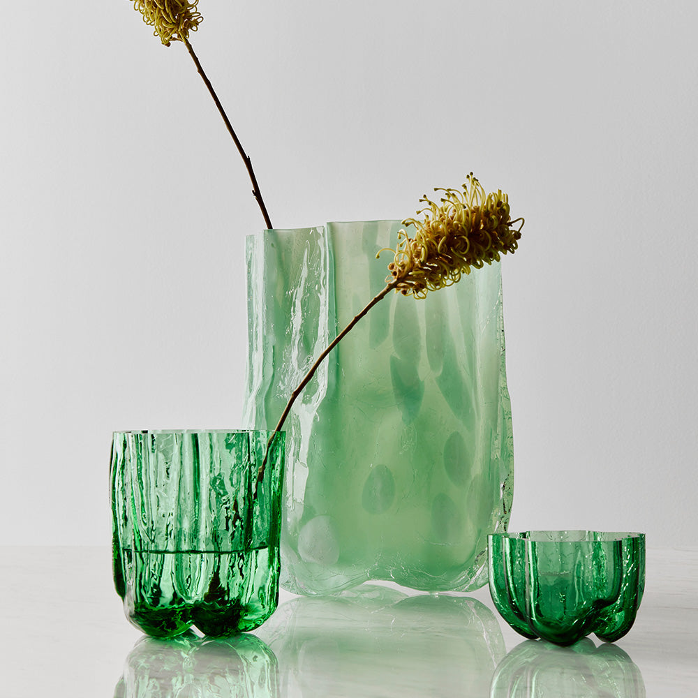 Set of green glassware with textured surfaces on a light gray background