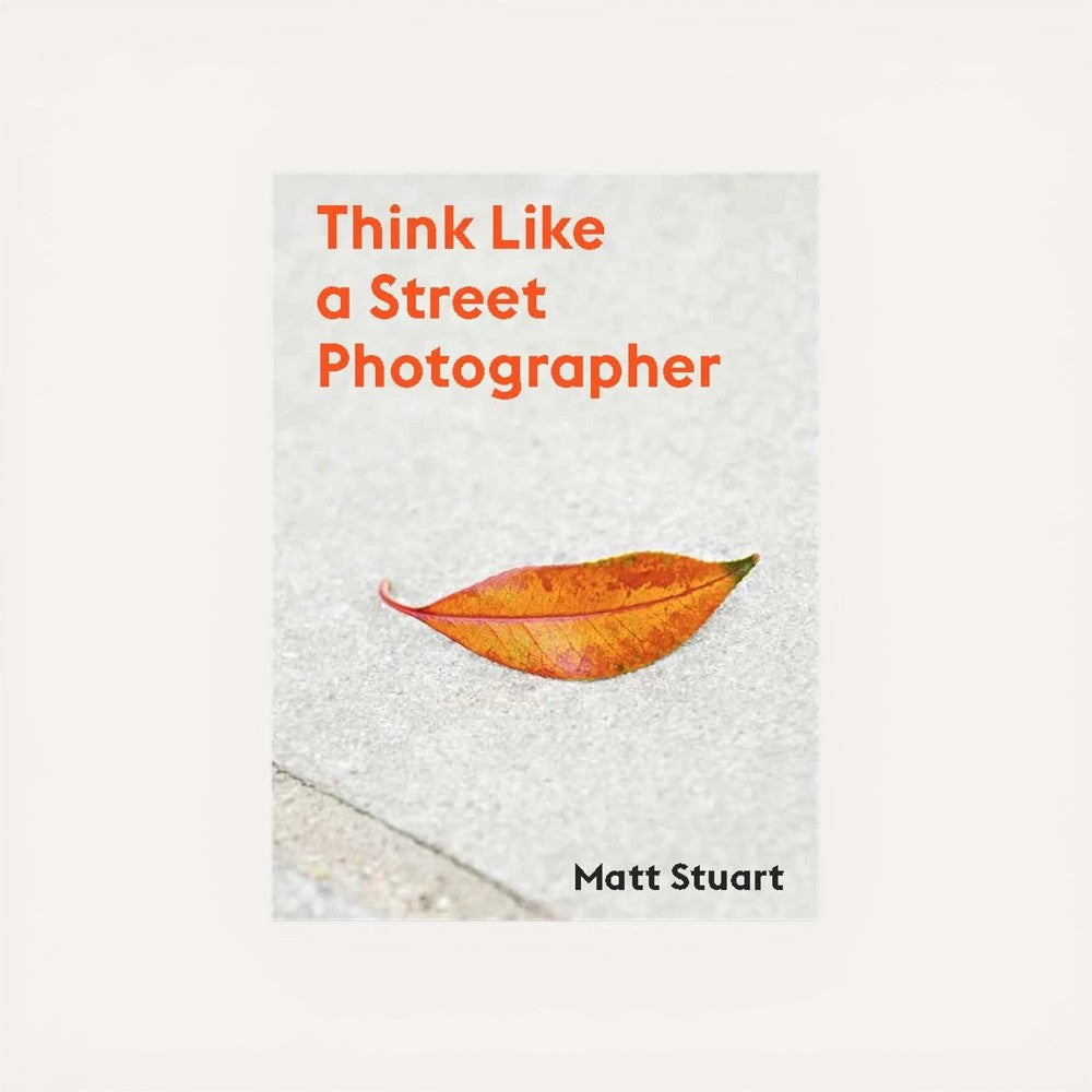 Book cover of 'Think Like a Street Photographer' by Matt Stuart with an orange leaf on a textured surface.