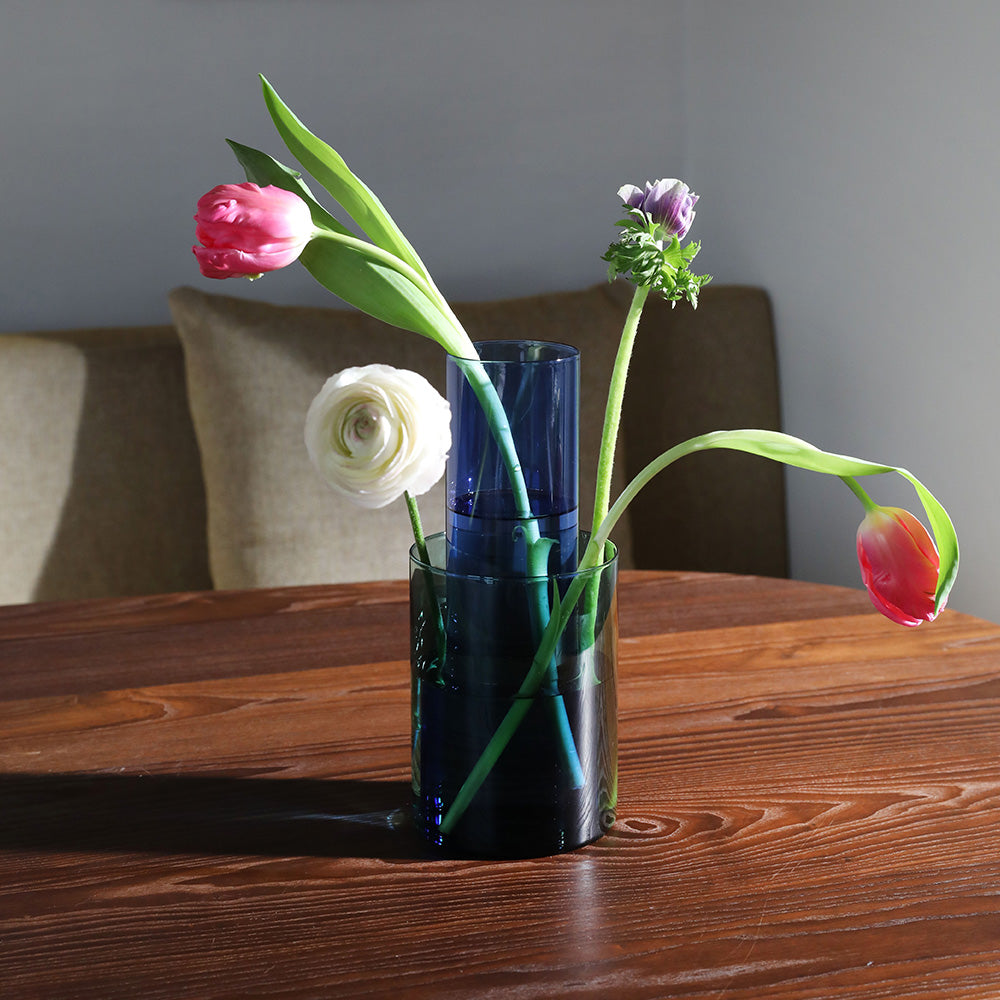 Vase with flowers on a wooden table against a neutral background