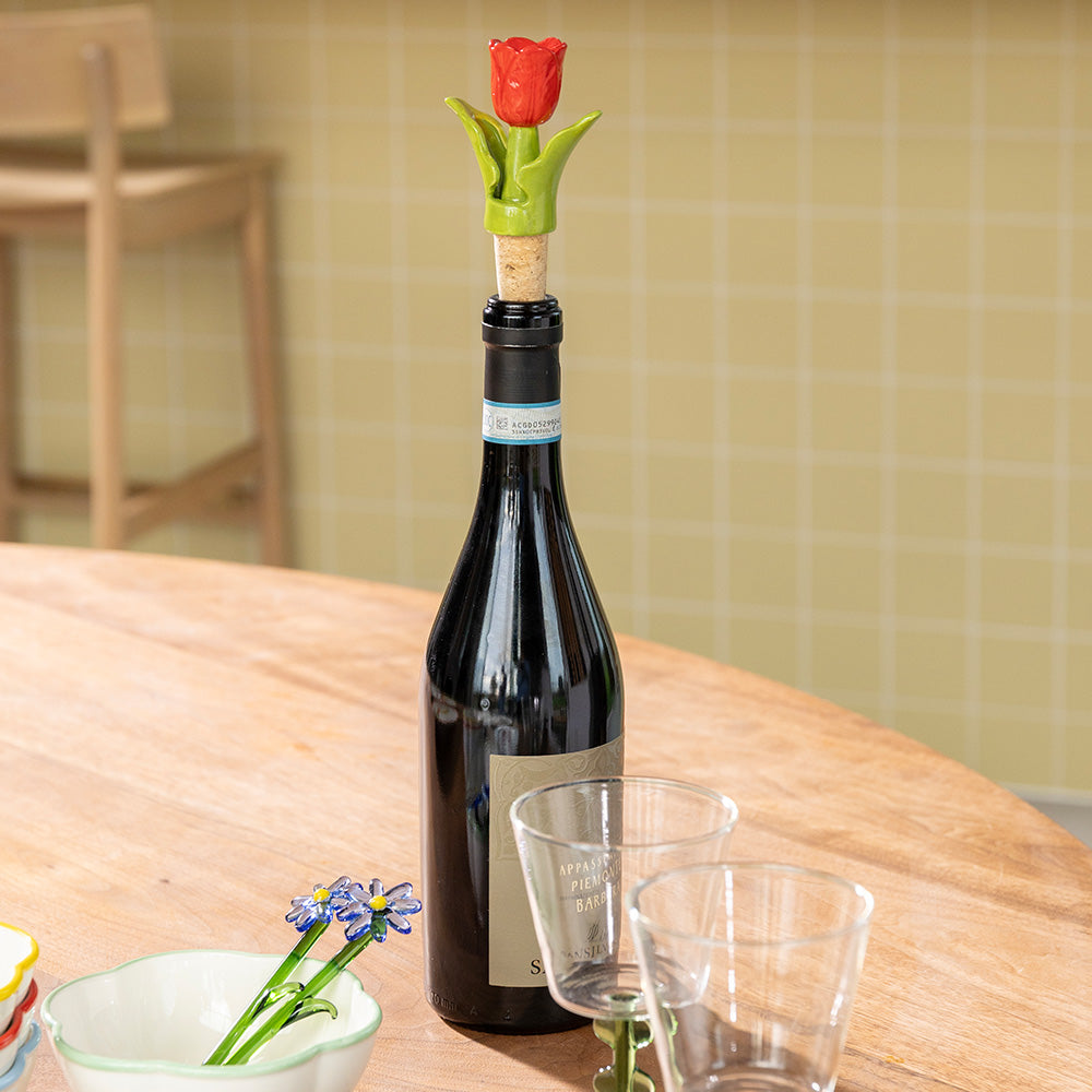 Wine bottle with a decorative tulip-shaped cork on a wooden table.