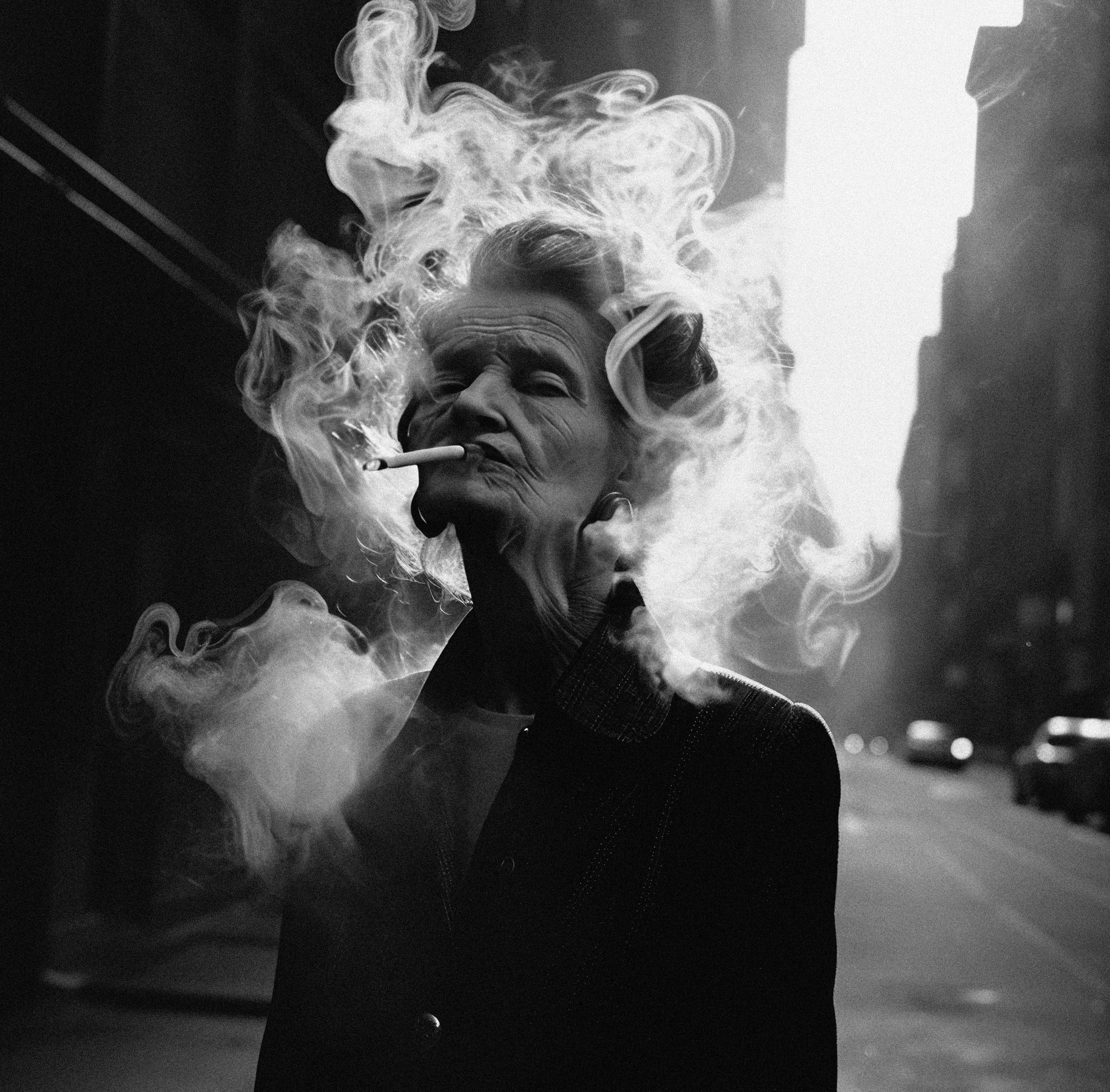 Motif by Edward Trevor - person smoking a cigarette with smoke swirling around, street scene in the background. 