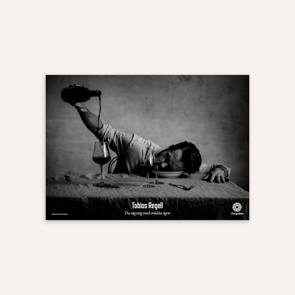 Black and white photo of a person lying on a bed with wine glasses and a bottle, with 'Tobias Regell' text.